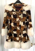 Front on-view of coat on hanger showing patchwork pattern, double-breasted buttons, hood and white trim.