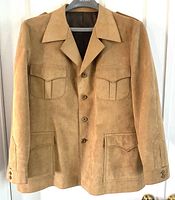 Full front view of the light brown suede blazer with buttoned front, flap pockets on chest and hips, wide lapels, and sleeves with button detailing.