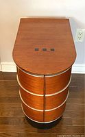 Front view of vintage Art Deco style side table with wood top and curved cabinet front.