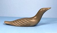 Left side view of soapstone bird carving showing profile and wing incisions