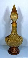 Full view of amber glass genie decanter with pointed stopper showing overall shape and amber color.