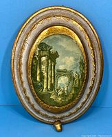 Full view of the oval Florentine wall music box showing the overall frame, pull string, and artwork.