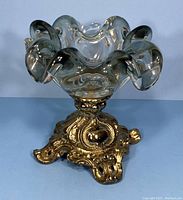 Clear Murano style art glass ashtray bowl with ruffled edges atop ornate brass stand shown from front angle.