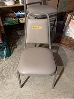 Front view of single beige chair with padded vinyl seat and backrest, metal frame.