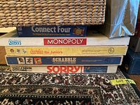 Stack of five classic board games including Connect Four, Monopoly, Chardee for Juniors, Scrabble for Juniors, and Sorry.