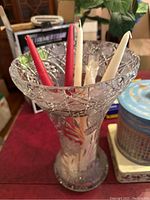 Crystal vase with red and white taper candles inserted, showing intricate cut design of the vase