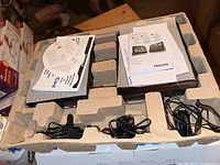 Two Philips portable DVD players placed side by side in molded packaging with manuals, cables, and adapters visible.