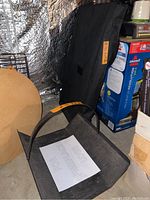 Photos of a used metal fireplace log holder with a curved handle, placed on a concrete floor with a paper sign that says 'FOR FIREPLACE LOGS'.