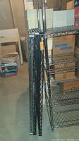 Side view showing three extra black metal wire shelves leaning against the shelving unit.
