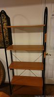 Full view of the metal frame shelving unit with five wooden shelves in light wood finish.