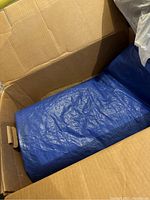 Blue synthetic tarp folded inside a cardboard box
