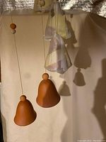Two large terracotta bell-shaped ceramic chimes hanging with wooden beads on strings.