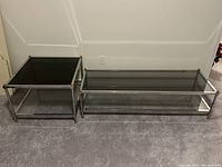 Two-piece set showing coffee table (long) and end table (square) side by side, silver metal frames and glass surfaces visible
