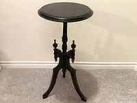 Full view of the three-legged black round bar height snack table