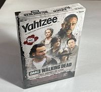 Front view of sealed boxed AMC The Walking Dead themed Yahtzee dice game showing character artwork and branding.