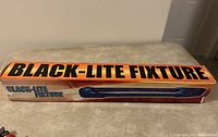 Box labeled 'BLACK-LITE FIXTURE' with orange, black and blue text and design.