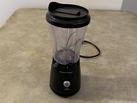 Front view of the Hamilton Beach black blender with blending jar attached showing pulse control button and power cord.