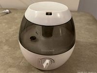 Front view of humidifier showing Honeywell logo, dark transparent water tank, white base with control dial.