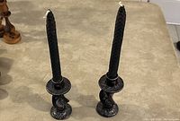 Pair of black soapstone candlestick holders with tall black candles inserted, showing spiral twisted shape and hand carved engravings.