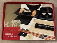 Photo of retail box showing brand and sushi set image with black ceramic pieces and wooden chopsticks.