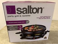 Front view of Salton party grill and raclette original packaging showing product name and key features.