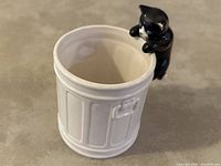Top angle showing inside of white ceramic trashcan shaped mug with black and white cat figurine handle.