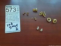 Overview of five pairs of small 10K gold earrings and one single clip earring laid out on table