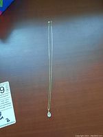 Full length of yellow gold box chain with pendant laid flat