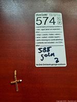 Close-up of gold cross pendant beside a label indicating 585 gold marking.