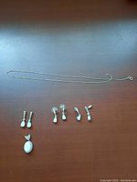 Full set laid out showing chain, earrings, and pendants on dark surface