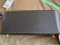 Closed black faux leather box with gold detailing containing Birks cutlery set.