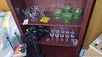 Shelves showing various glassware including sundae, sherbet, shot, and aperitif glasses plus resin animal figurine and plastic tokens.