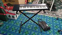 Full view of Casio CA-110 keyboard on X-style stand with book bag on the floor beside it