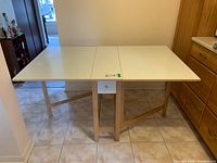 Full front view of cream laminate wood kitchen table with both extensions down.