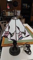 Lamp with metal base and stained glass style shade, showing floral design and metal base details.