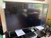 Front view of LG 49-inch flat-screen television on black stand with papers and remote on top.