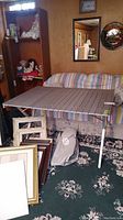 Photo showing metal folding picnic table set up with canvas carrying bag below it and surrounding items