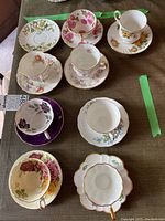 Top view of all eight teacups each placed on respective saucers showing various floral patterns and colors.