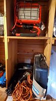 Wooden shelf holding two red work lights with protective metal cages and padded handles, and black hard case with LAZERPRO label