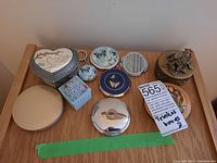 Photo showing all the trinket boxes, compact mirrors, keychain laid out on wooden surface