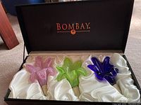 Boxed set of three Bombay wine stoppers, pink, green, and blue glass tops in original black box with satin lining