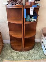 Two wooden 3-tier corner shelves side by side, showing size and rounded fronts with smooth finish.