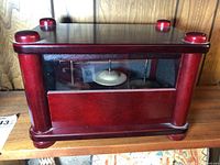 Front view of wooden falling rain chime box, showing the tambourines inside and transparent front panel.