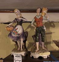 Front view showing both figurines side by side on a surface against a wall.