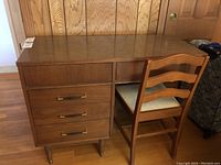 Full front view of mid-century modern wood desk and vinyl seat chair.