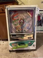 Full front view of the white vintage pachinko machine with colorful circular playfield and coin slot at the bottom.