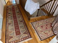 Photo showing both Persian style runner rugs in a hallway near stairs, highlighting their color, pattern, and placement.