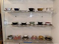 Three shelves displaying sixteen assorted teacup and saucer sets