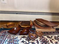 Wide shot showing entire collection of trays and serving items on rug, including trays, bowls, rolling pin, and a small wooden bowl with painted detail
