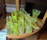 Overall group of nine vaseline glass shoes and boots on wicker shelf